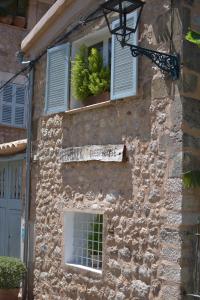 un edificio in pietra con due finestre e un cartello sopra di Ecocirer Guest House a Sóller