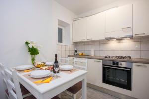 a white kitchen with a table with a bottle of wine at Apartment Marsela in Šibenik