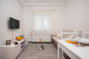 a white living room with a couch and a tv at Apartment Marsela in Šibenik