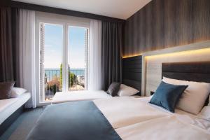 a hotel room with two beds and a large window at Dependences - San Simon Resort in Izola