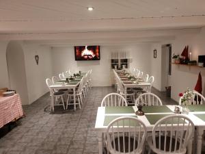 uma sala de jantar com mesas e cadeiras brancas e uma lareira em Landet Bed and Breakfast em Tomelilla