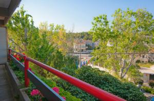 a balcony with a red railing and flowers at Apollonia Hotel Apartments in Varkiza