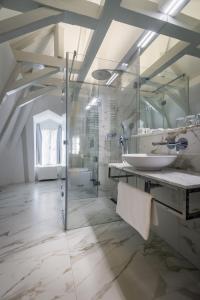 uma casa de banho branca com um lavatório e um chuveiro em Hotel Waldstein em Praga