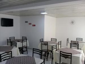 Porto Seguro Office Hotel في باورو: غرفة طعام مع طاولات وكراسي وتلفزيون
