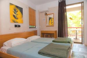 a hotel room with two beds and a window at Apollonia Hotel Apartments in Varkiza