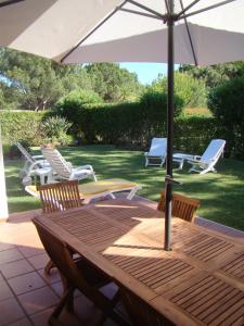 a wooden table and chairs with an umbrella at SOLAR DO GOLFE - Vilamoura in Vilamoura