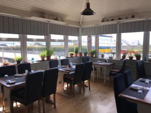 a dining room with tables and chairs and windows at Westend Bar & select accommodation in Fenit