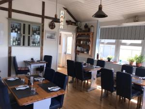 uma sala de jantar com mesas de madeira e cadeiras pretas em Westend Bar & Restaurant em Fenit