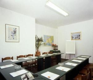 una habitación con mesas, sillas y una pared blanca en Hotel Riviera, en Celle Ligure