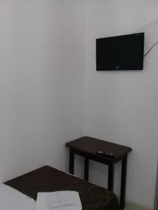 Habitación con mesa y TV en la pared. en Porto Seguro Office Hotel, en Bauru