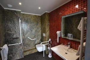 y baño con lavabo, ducha y azulejos rojos. en Hôtel De Calais en Le Tréport