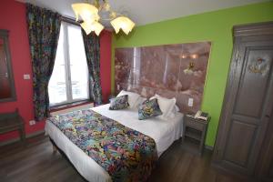 a bedroom with a large bed with colorful walls at Hôtel De Calais in Le Tréport