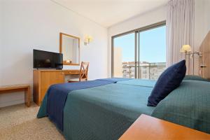 a bedroom with a bed and a desk and a television at azuLine Hotel S'Anfora & Fleming in San Antonio