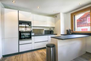 a kitchen with white cabinets and a black counter top at PORTES DU PLENEY 101 in Morzine