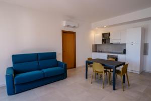 a living room with a blue couch and a table and chairs at Residence Marinella in San Vito lo Capo