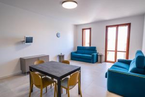 a living room with blue furniture and a table and chairs at Residence Marinella in San Vito lo Capo