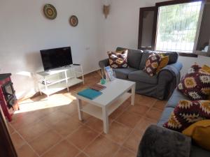 sala de estar con sofá y mesa en Cave Holidays Andalucia, en Los Carriones