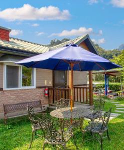 a table and chairs with an umbrella on a yard at 蓬萊生態農場仙山民宿 in Nanzhuang