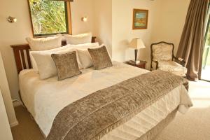 a bedroom with a large bed and a chair at Whakaipo Lodge in Taupo