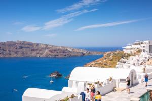 a group of people standing on a ledge looking at the ocean at Stelios Rooms in Oia