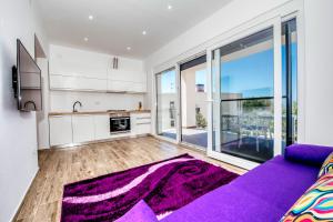 a living room with a purple couch and a kitchen at Boutique Villa Nirvana 2, Proboj 25 in Pag