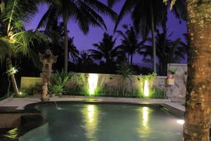 a swimming pool with lights in a backyard at night at Dewa House Bisma in Ubud