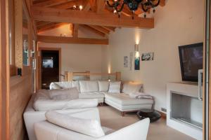 a living room with white couches and a tv at FARONNIERE 5 in Morzine