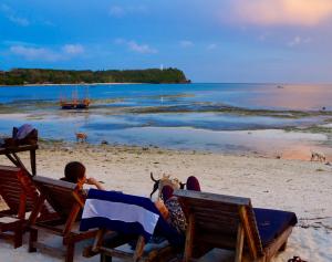 a couple of people sitting in chairs on a beach at Sabas Beach and Campsite in Siquijor