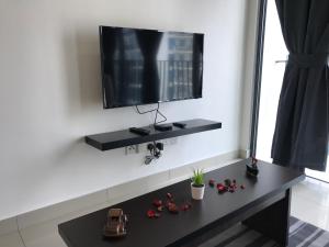 een zwarte tafel met een televisie op een witte muur bij CozyStudio Trefoil Setia Alam in Shah Alam