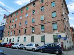 un grande edificio in mattoni con macchine parcheggiate di fronte di Casadei Guest House Stazione Bologna a Bologna