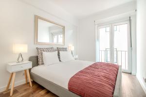 1 dormitorio blanco con 1 cama grande y espejo en Lisbon Stay at Santo Antonio Flat, en Lisboa