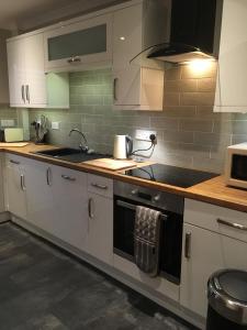 a kitchen with white cabinets and a stove top oven at Kennedy Terrace; Modern 2 bedroom house, central in Stornoway