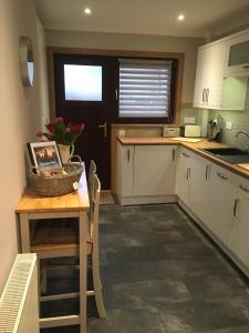 a kitchen with white cabinets and a table with a basket on it at Kennedy Terrace; Modern 2 bedroom house, central in Stornoway