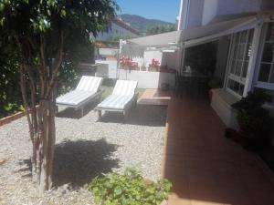 patio z dwoma białymi ławkami na domu w obiekcie agradable y familiar w mieście Premiá de Mar