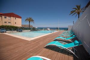 a row of lounge chairs next to a swimming pool at Hotel Sol de Jávea in Jávea
