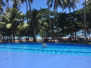 a person swimming in a pool with palm trees at Praia do Forte - Frente ao Mar in Praia do Forte +6 photos