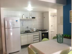 a kitchen with a white refrigerator and a table at Praia do Forte - Frente ao Mar in Praia do Forte