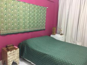 a bedroom with a green bed and pink walls at Praia do Forte - Frente ao Mar in Praia do Forte