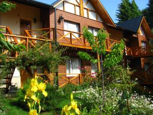 a wooden house with flowers in front of it at Puente Austral in San Carlos de Bariloche