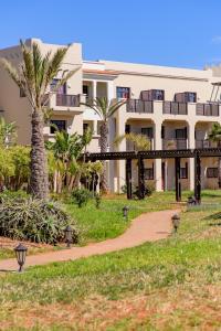 a view of a building with palm trees and a walkway at Oasis Beach & Spa - Blue Pearl in Saïdia