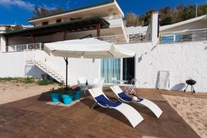 a couple of chairs and an umbrella on a patio at Terrazza Sul Mare in Trappeto