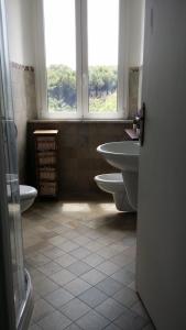 a bathroom with two sinks and a toilet and two windows at Carpe Diem Ancona in Ancona