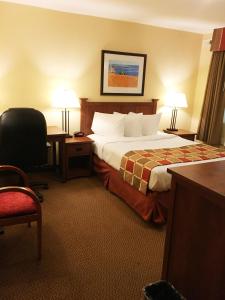 a hotel room with a bed, desk, chair and a lamp at Charlottetown Inn & Conference Centre in Charlottetown