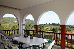 Villa Maria by RentalsPro - Ouranoupoli Halkidiki في أورانوبوليس: طاولة بيضاء وكراسي على شرفة مطلة
