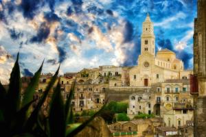 a large building with a clock tower and a church at L' Infinito dei Sassi in Matera