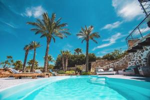 a pool at a resort with palm trees at Villa Di Maria in San Vito lo Capo