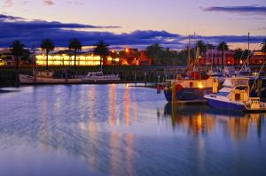 een groep boten aangemeerd in een jachthaven 's nachts bij Senator Motor Inn in Gisborne