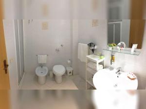 a white bathroom with a toilet and a sink at Appartamenti Monacò in San Vito lo Capo