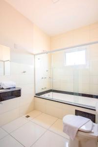 a white bathroom with a tub and a toilet at Gabirá Hotel in Buritama