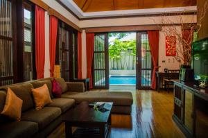 a living room with a couch and a tv at Kirikayan Residences Koh Samui in Mae Nam